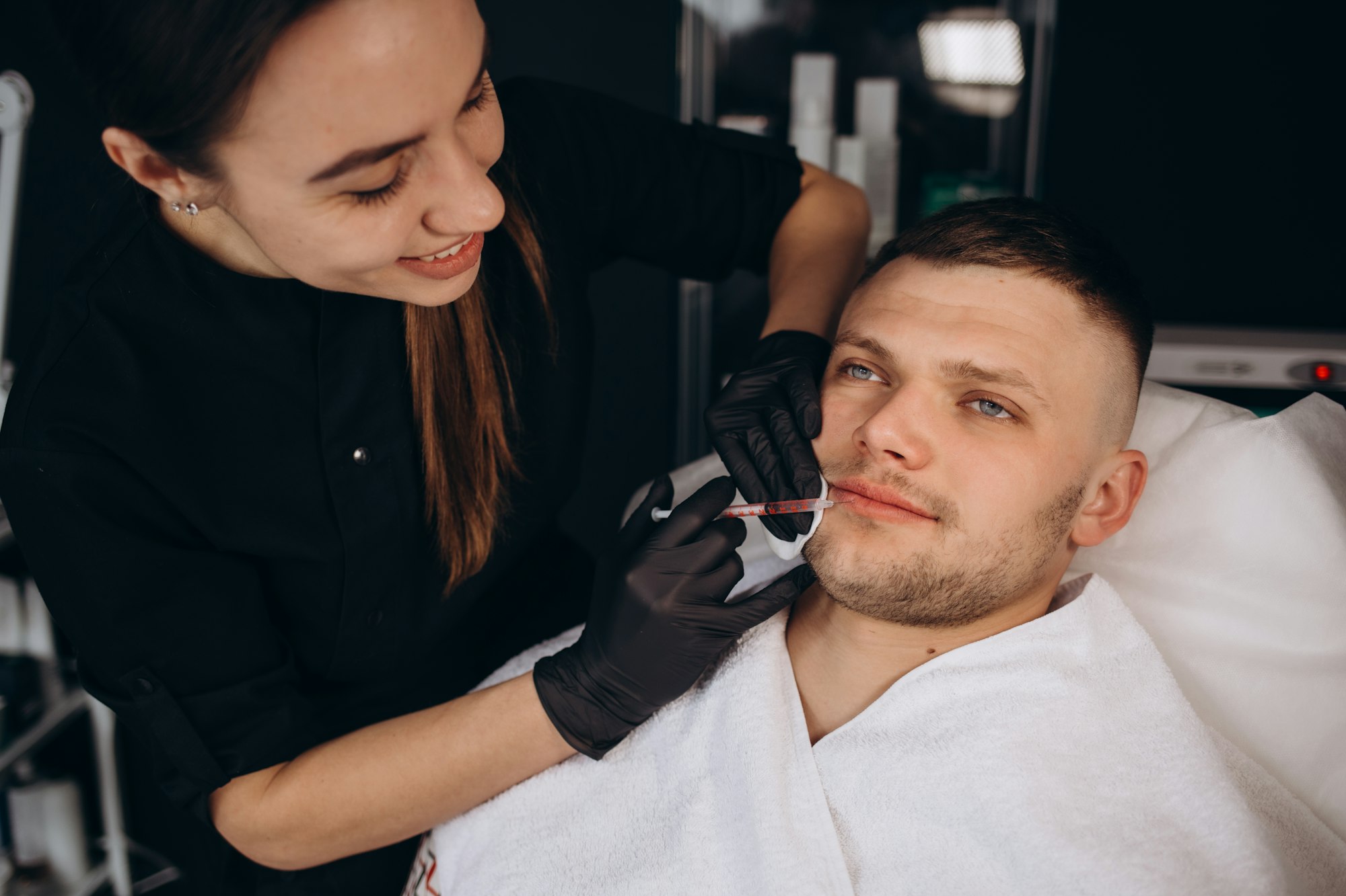 Beautician does filler injection to middle aged person at lip augmentation procedure in clinic